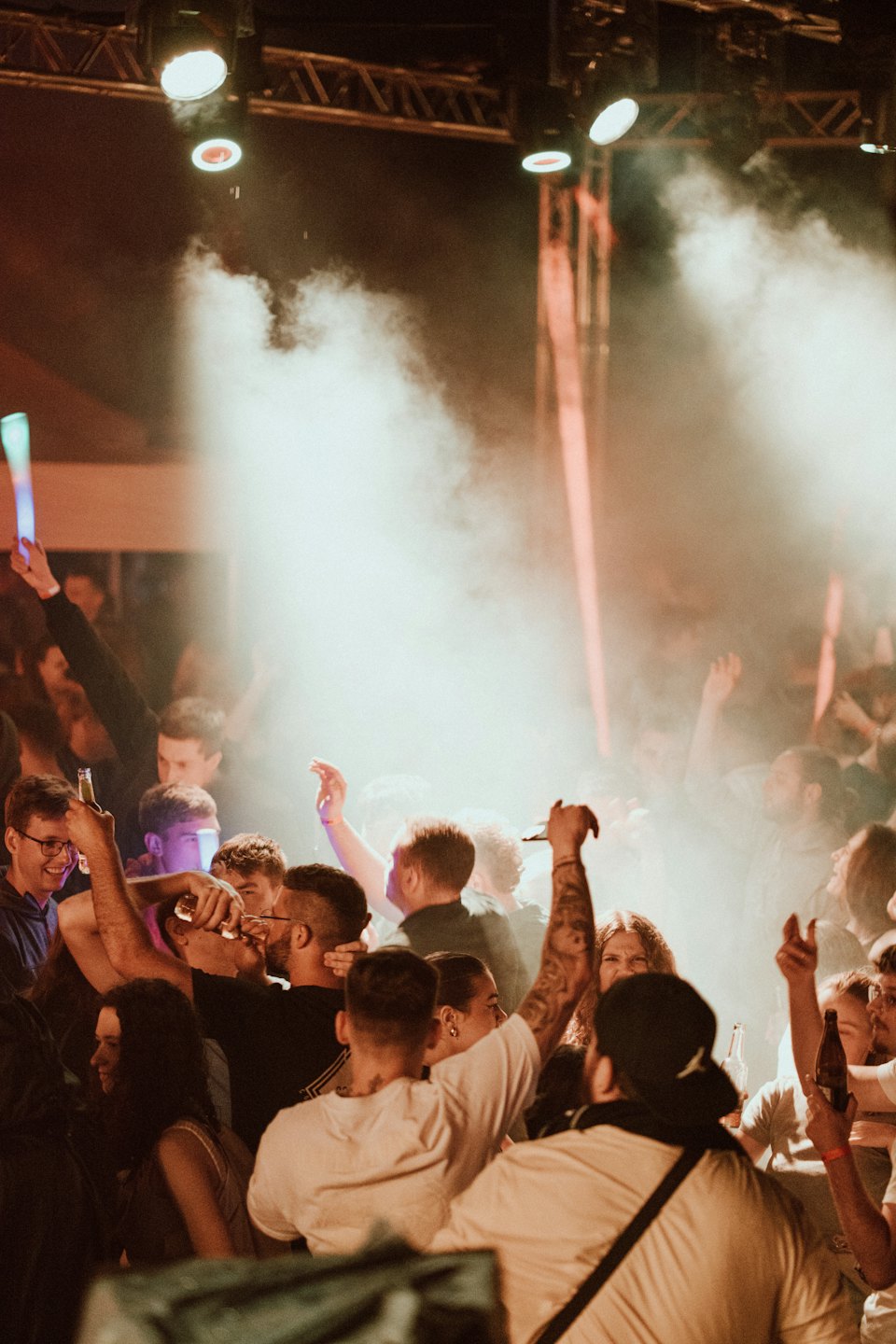 Menschen tanzen und heben die Hände auf einem vollen Konzert.
