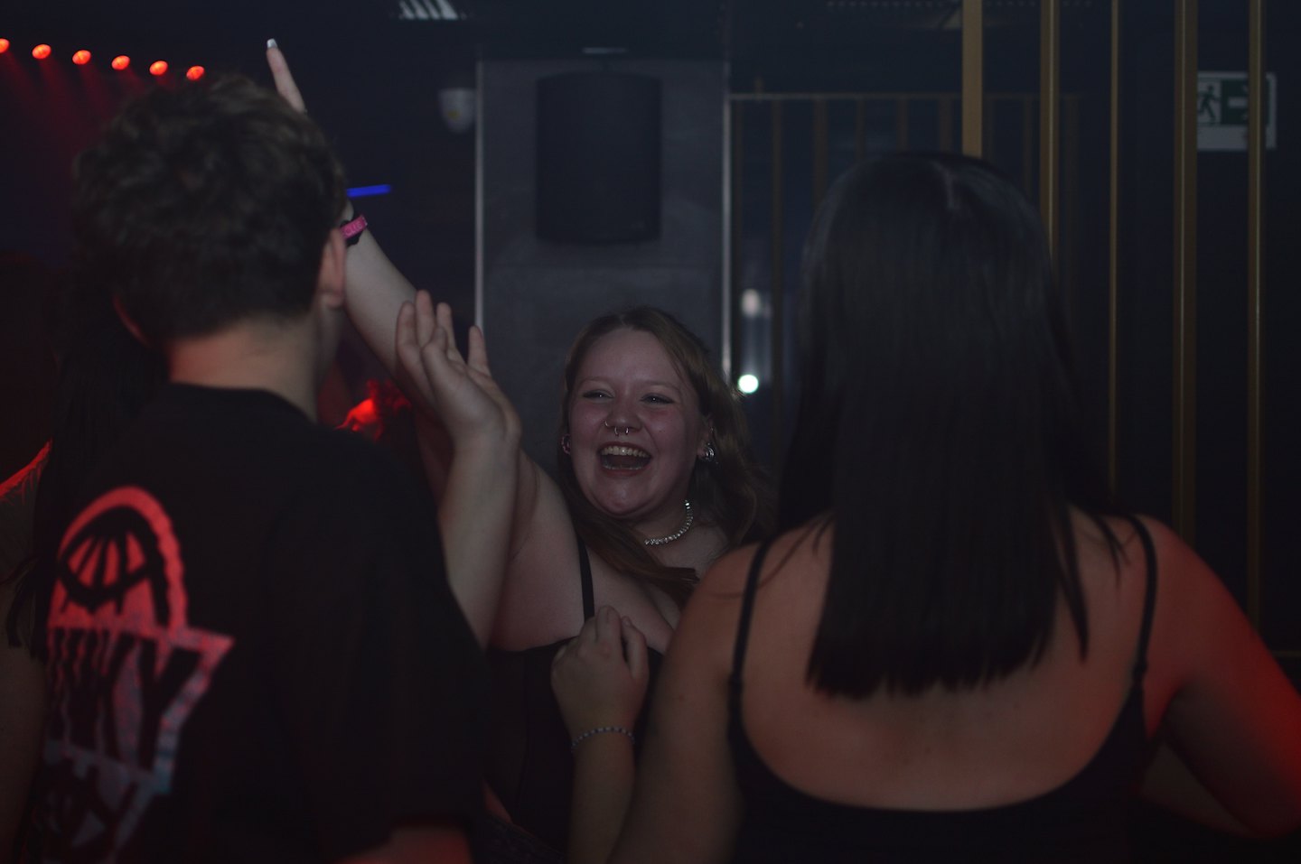 Junge Erwachsene tanzen und lachen in einem lebhaften Nachtclub.