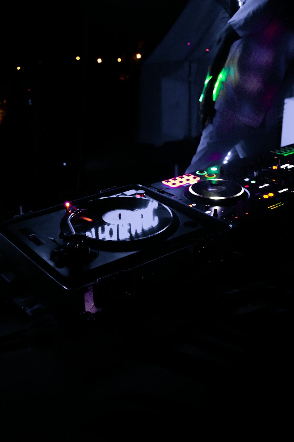 DJ legt Musik auf Plattenspielern mit bunten Lichtern auf.